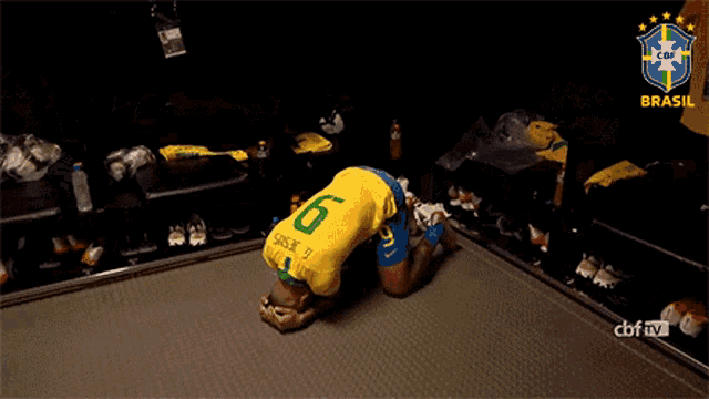 a soccer player kneeling down in a locker room with the word brasil behind him