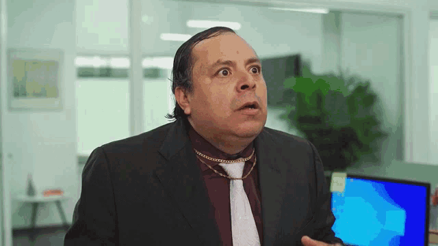 a man in a suit and tie is making a funny face in front of a computer .