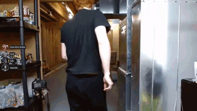 a man in a black shirt is walking down a hallway in front of a green brick studios sign
