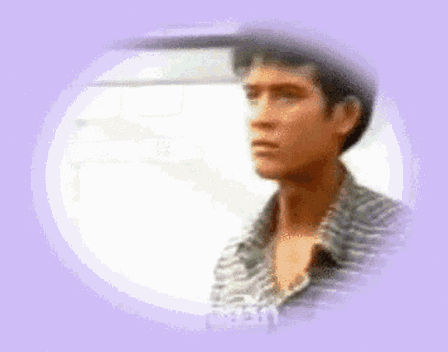 a man in a plaid shirt is standing in front of a white wall