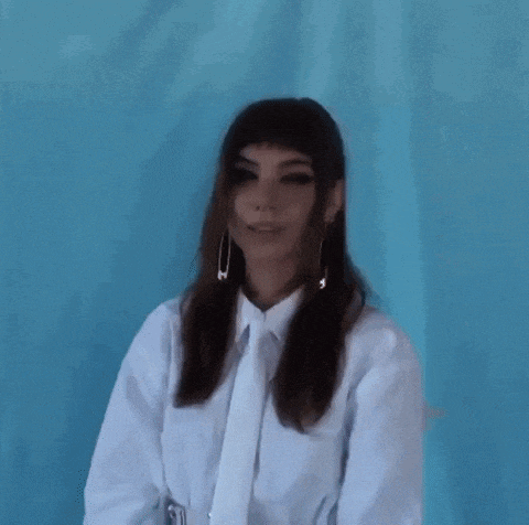 a woman wearing a white shirt and tie has a safety pin in her earring