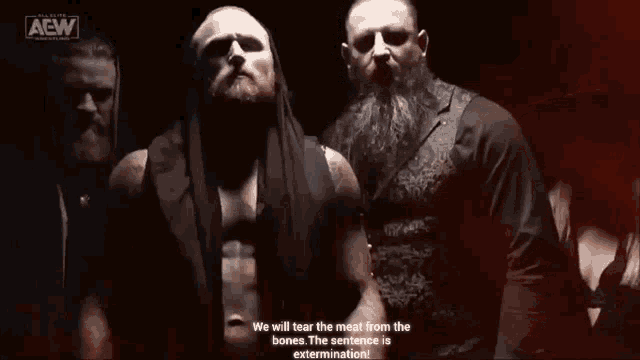 a group of wrestlers are standing next to each other in a dark room with a red background .