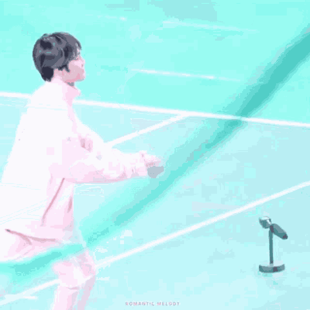 a person is kneeling down on a tennis court while another person throws a ball .