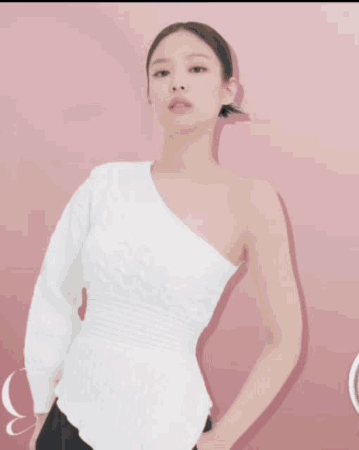 a woman in a white one shoulder top is standing on a pink background