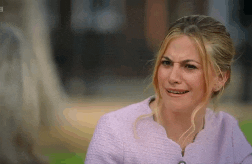 a woman in a pink jacket is making a funny face .