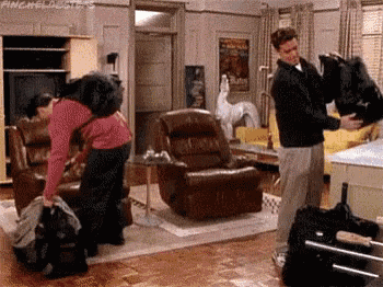 a man and a woman are standing in a living room holding a bag .