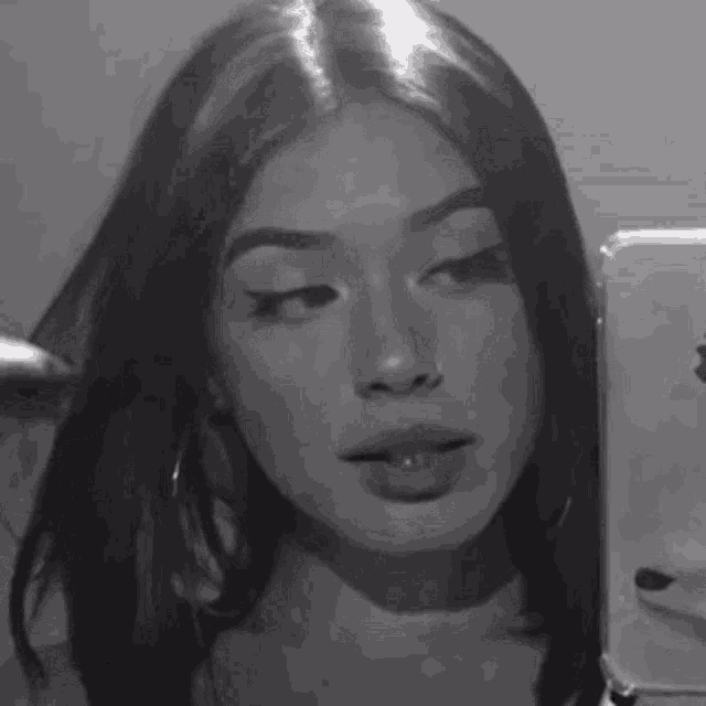 a black and white photo of a girl taking a selfie with her cell phone .