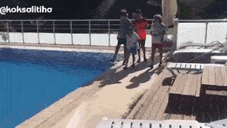 a group of people are standing next to a swimming pool