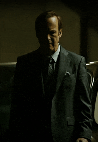 a man in a suit and tie is standing in the shadows