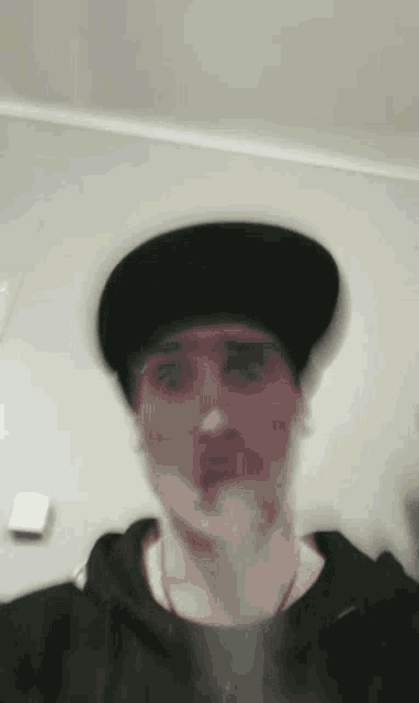 a blurry picture of a man wearing a hat and a hoodie .