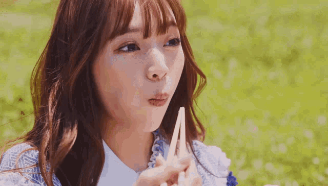 a woman is eating food with chopsticks in a park .