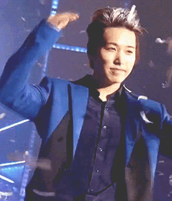 a man in a blue suit and black shirt is standing on a stage
