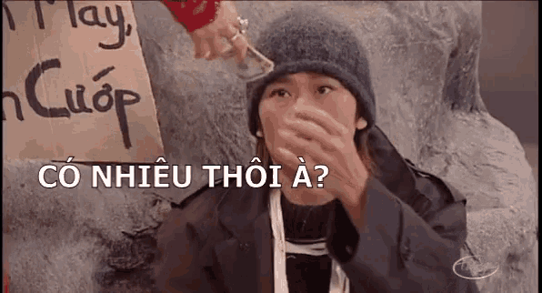 a person is giving money to a homeless person who is covering her mouth .