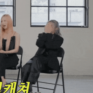 a woman covering her face while sitting next to another woman with chinese writing on the floor