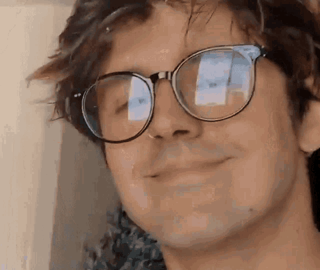 a close up of a man wearing glasses smiling .