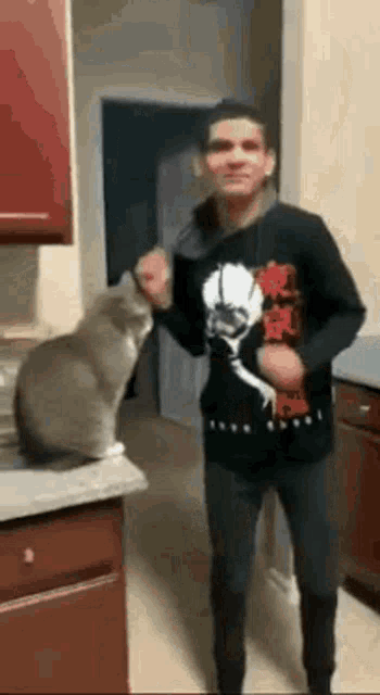 a man and a cat are dancing in a kitchen .