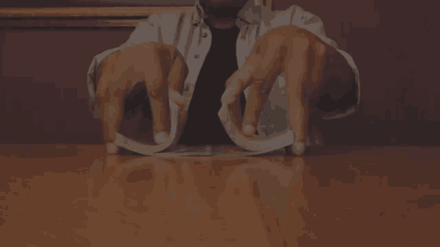 a man is sitting at a table playing a game of cards with his hands .