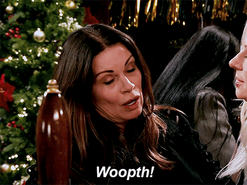 a woman is sitting in front of a christmas tree and saying woopth