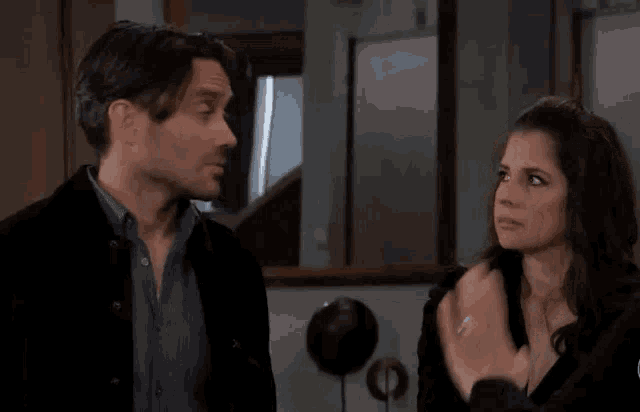 a man and a woman are standing next to each other in a room and talking to each other .