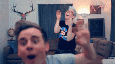 two men are dancing in a living room with a deer head on the wall .