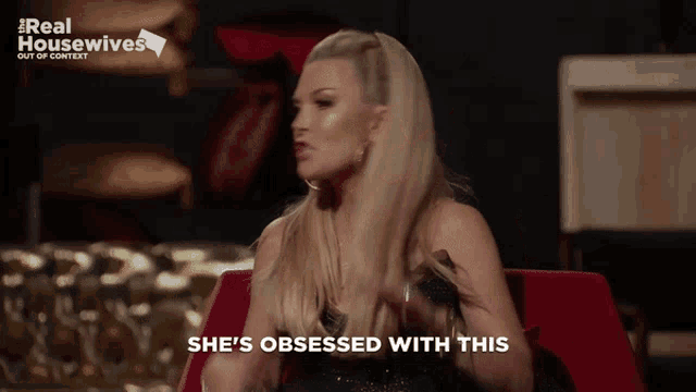 a woman is sitting in a red chair with the words she 's obsessed with this behind her