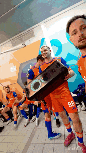 a group of soccer players are standing in a locker room and one has the number 99 on his shorts