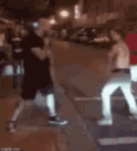 a blurry picture of two men fighting on the sidewalk .