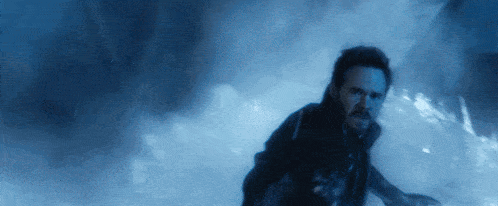 a man with a beard is running in a dark room