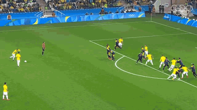 a soccer game is being played on a field with the olympics logo on the side