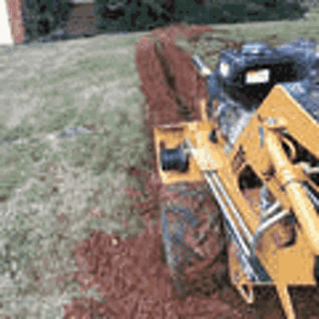 a yellow tractor is digging a hole in the ground .