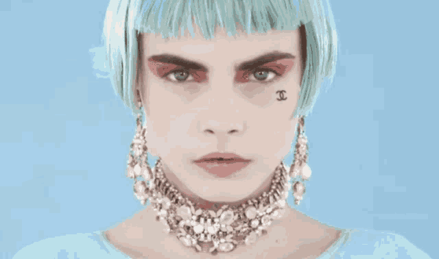 a woman with blue hair has a chanel tattoo on her face