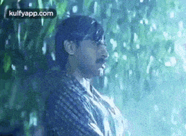 a man in a plaid shirt is standing in the rain with his shirt wet .