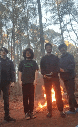 a group of young men standing in front of a fire with one wearing a shirt that says ' abercrombie & fitch '