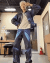 a man in a blue jacket and blue pants is standing in a room with his hands on his head .