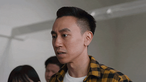a man wearing a yellow and black plaid shirt looks at something