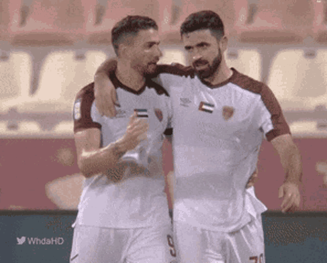 two soccer players hugging each other on a field