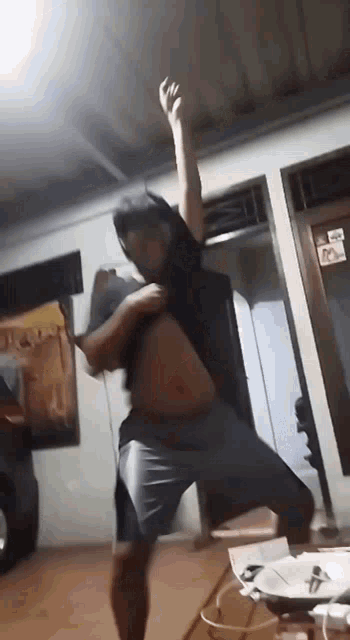 a man is dancing in a room with his shirt off