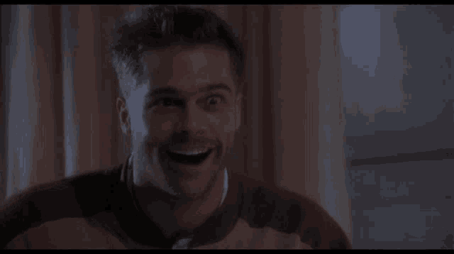 a close up of a man 's face smiling in a dark room