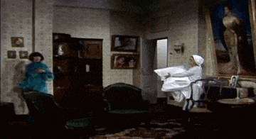 a woman is holding a pillow in a living room while another woman stands in the background .
