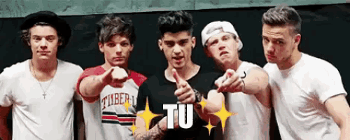 a group of young men are pointing at the camera and one of them has the word tu on his shirt .