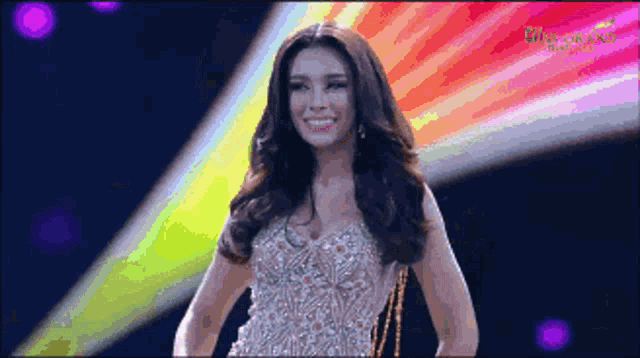 a miss grand thailand contestant smiles while walking on stage