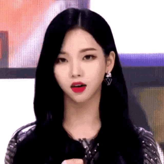 a woman with long black hair and red lips is wearing earrings and a sequined dress .