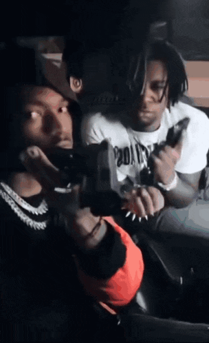 two men are holding guns in a dark room .