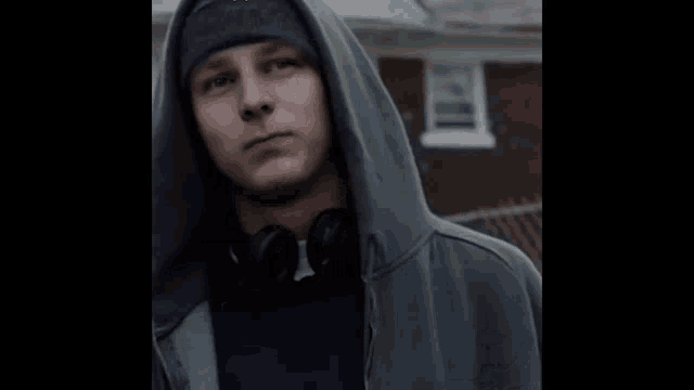 a man wearing headphones and a hooded jacket is giving the middle finger .
