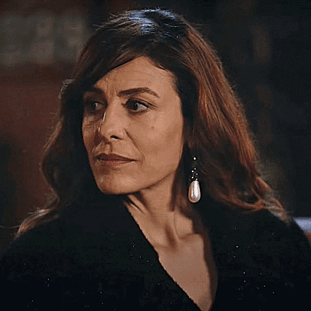 a woman wearing pearl earrings and a black top
