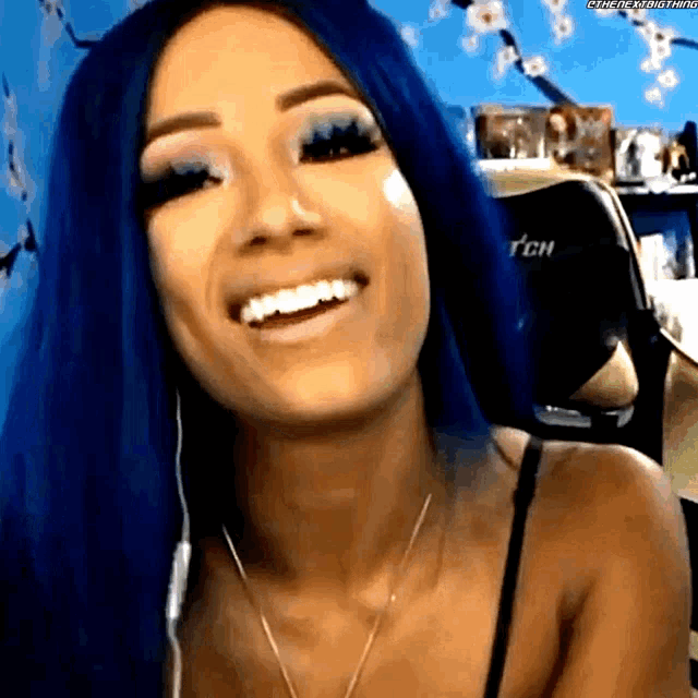 a woman with blue hair is smiling and wearing headphones and a bra .