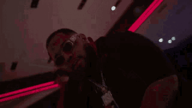 a man is standing in front of a microphone in a dark room with red lights .