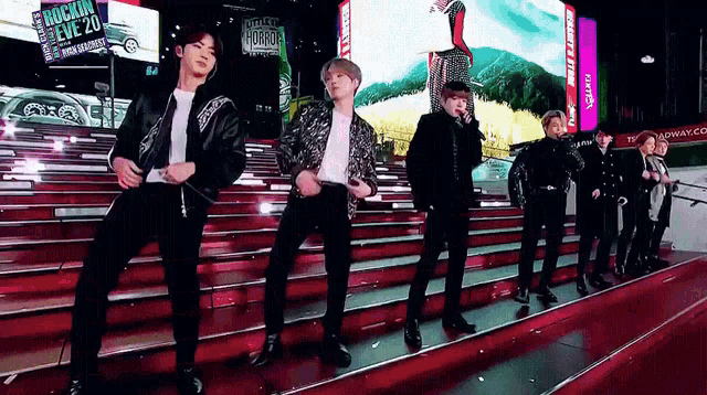 a group of young men are dancing on a red carpet in front of a sign that says rockin ' five 20