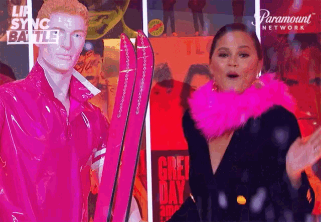 a woman wearing a pink boa is standing in front of a paramount network poster ..