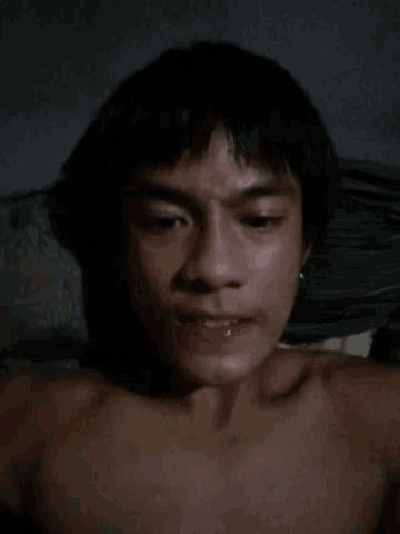 a man without a shirt is taking a selfie with his eyes closed